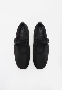 Scarpe Mary Jane nere realizzate in tessuto a rete, con punta tonda e una fascetta con fibbia sopra il collo del piede. Design con suola piatta.
