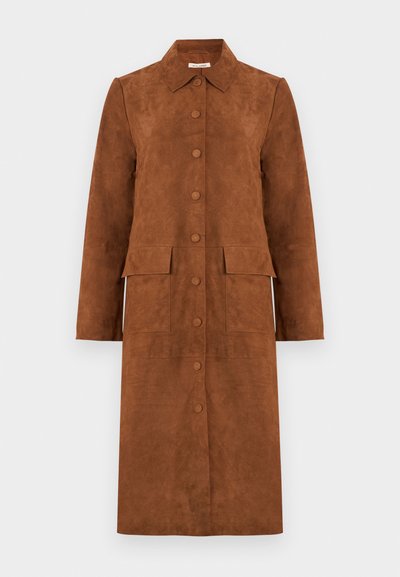 Καφέ μακρύ σουέντ παλτό με γιακά, μπροστινό κούμπωμα με κουμπιά και δύο μεγάλες τσέπες με καπάκια σε απλό φόντο.