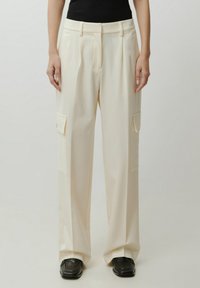 Beige wijde broek van gladde stof, met twee voorzakken, een vlakke voorkant, plooien en een getailleerde pasvorm.