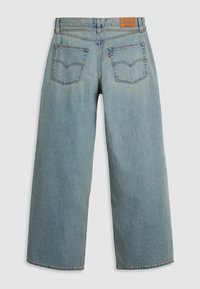 Jean en denim bleu clair, coupe droite, avec deux poches arrière, une étiquette de marque en cuir marron sur la ceinture et des détails de couture visibles.