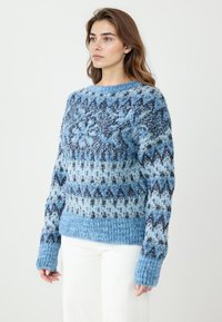 Gestrickter Pullover in unterschiedlichen Blautönen, mit einem geometrischen Muster, gerippten Bündchen und einem breiten Bund. Hergestellt aus weichem, strukturiertem Garn.