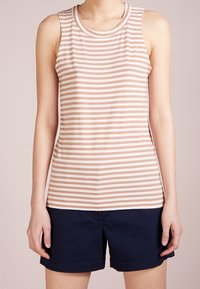 Ærmeløs tanktop i lyserød med horisontale hvide striber; rund halsudskæring; blødt, strækbart stof. Kombineret med mørk marinblå shorts.