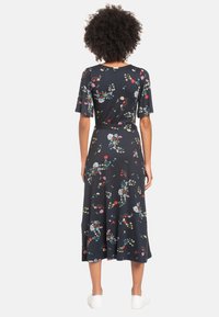 Blommig midiklänning med marinblå bakgrund, korta ärmar, markerad midja och utställd fåll. Har färgglada blommönster över hela.