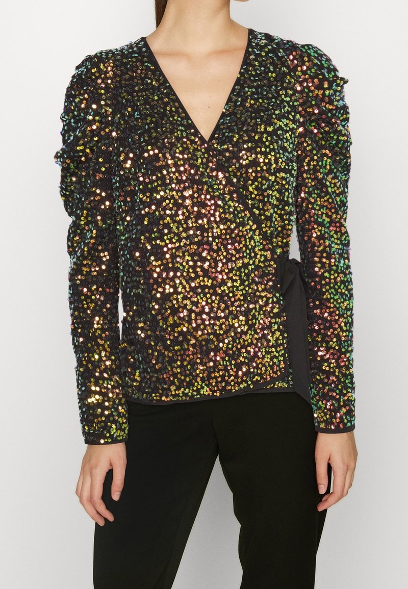 Top avvolgente nero con paillettes, scollo a V profondo, spalle texture e dettaglio in vita legato. Le paillettes hanno superfici riflettenti multicolori.