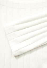 Witte ribbelstof met geplooide secties, voorzien van subtiele stiksels. De textuur lijkt glad en licht van gewicht.