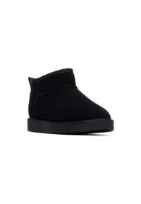 Botas negras hasta el tobillo de suave ante, con un diseño simple, un perfil bajo y una suela de goma texturizada para mayor agarre.