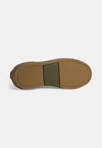 Schuhsohle mit einem hellbraunen Gummiäußeren, kontrastiert durch ein grünes Panel in der Mitte und einer strukturierten Oberfläche für besseren Grip. Glatte Kanten.