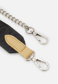 Cinghia in tessuto nera con un accento in pelle beige, dotata di catene in metallo argentato e due ganci a scorrimento per il fissaggio.