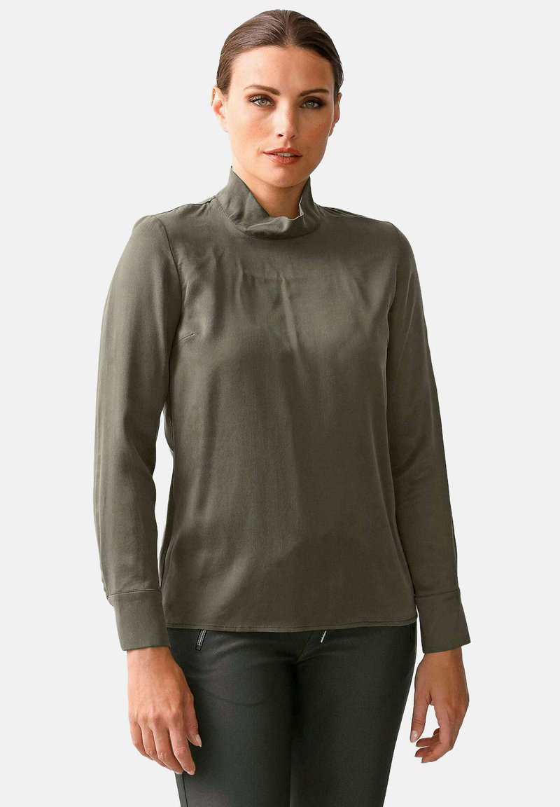 Olivgrünes Langarmhemd mit ste Hend. Glatter Stoff, taillierte Passform und gepuffte Ärmel. Minimalistischer Stil, keine Muster oder Metallteile.