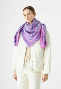 Paarse en roze patroon sjaal, driehoekige vorm, met franjes; gedragen over een licht denim jacket, met een zachte textuur en een gedurfde kleurcontrastering.