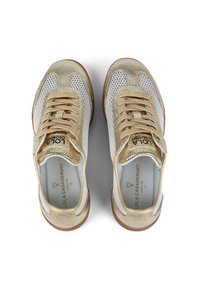 Zlaté a bílé síťované tenisky s texturovaným povrchem, s béžovými tkaničkami a hnědou gumovou podrážkou. Logo značky viditelné na jazyku.