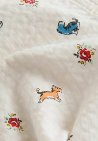 Tessuto con sfondo bianco caratterizzato da motivi ricamati di cani in blu e arancione, oltre a rose rosse e accenti floreali.