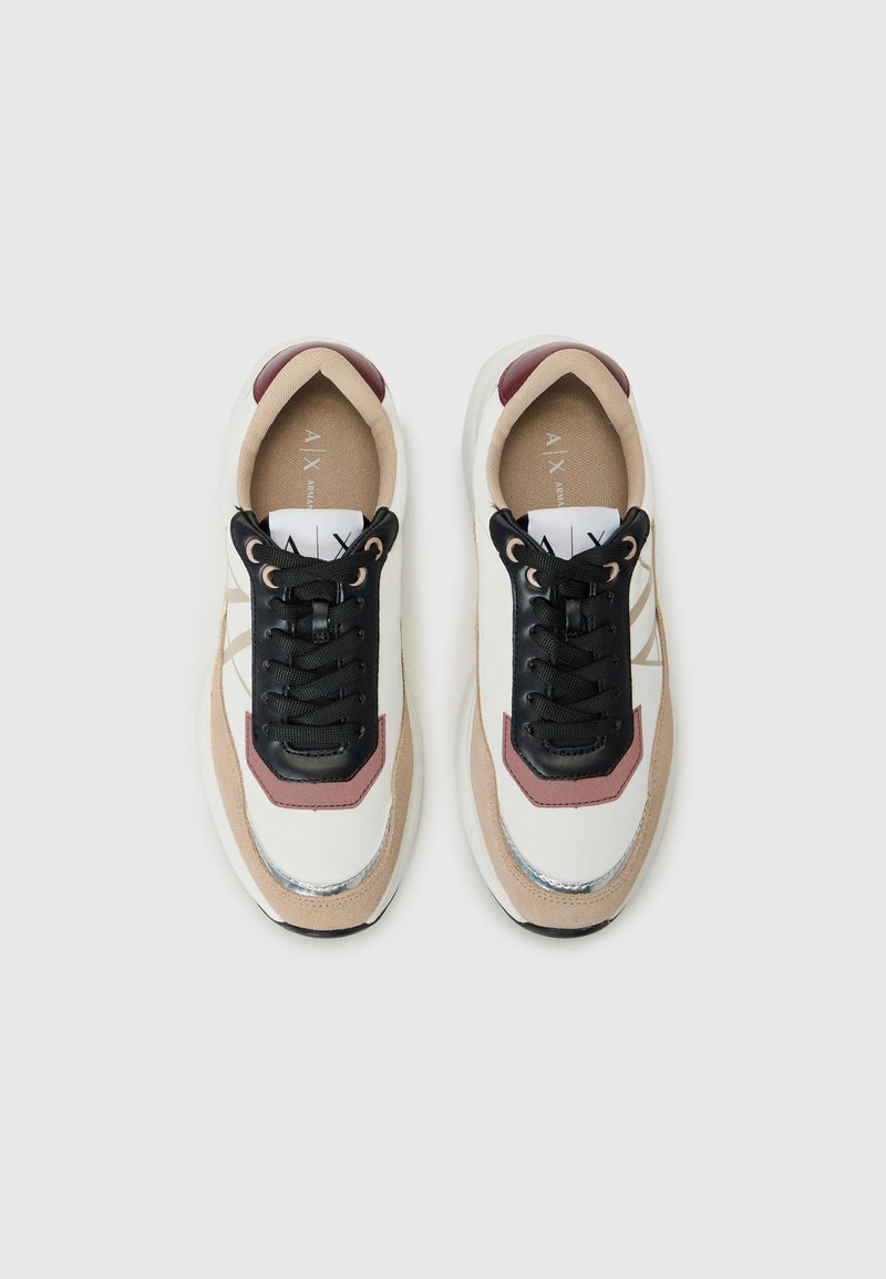 Zapatillas con una parte superior de malla blanca y beige, cordones negros, detalles en burdeos y adornos plateados en la suela. Punta redonda, plantilla acolchada.