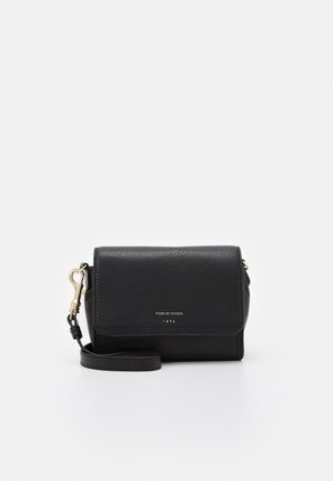Petit sac bandoulière en cuir texturé noir avec fermoir et sangle dorés, « Tiger of Sweden 1903 » embossé en or sur le rabat avant.