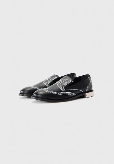 Black leather shoes featuring a decorative white pattern around the edges, with an elasticated opening and a low, textured heel.