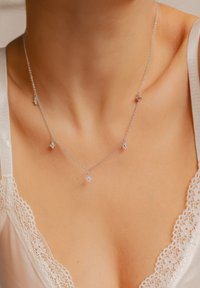 Srebrny naszyjnik z delikatnym łańcuszkiem, złożony z pięciu małych zawieszek w kształcie gwiazdek, z każdą ozdobioną błyszczącym kamieniem szlachetnym.