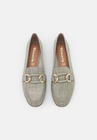 Mocassins vert clair avec une tige en tissu texturé, ornés d'une grande chaîne dorée et d'une lanière en cuir lisse. Intérieur marron.