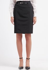 Černá elegantní sukně s přiléhavým střihem, detaily v pase a vertikálními švy. Kombinována s černými lodičkami z lakované kůže a světle zbarvenou blůzou.