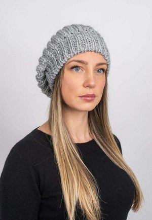 Light gray knitted beanie featuring a ribbed design and slouchy fit, made from soft yarn, worn on a model with long hair.