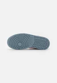 Blue rubber sneaker sole with textured grip patterns, circular logo, and zigzag design, featuring grooves for traction and support.