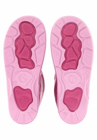 Roze rubberen schoenzolen met gestructureerde patronen, met een combinatie van lichtere en donkere roze gebieden. Hierop zijn opvallende ribbels en merkvermeldingen aanwezig.