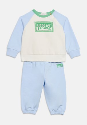 Ensemble deux pièces pour enfants avec pantalon bleu clair et haut manches longues blanc et bleu avec un logo Versace vert sur la poitrine.