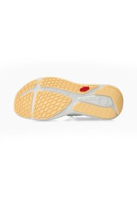 Semelle de chaussure avec motif de grip texturé beige, base blanche, étiquette rouge "AllGrip" et fonctionnalité "Shock Absorber" indiquée près du talon.
