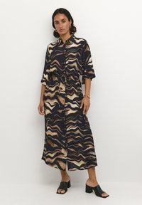 Vestido largo, abotonado en tonos azul marino y beige con patrones de olas, ajustado en la cintura, con mangas cortas y una silueta fluida.