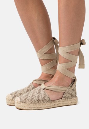 Espadrilles beiges en tissu à motifs, avec semelles en jute et brides croisées en toile autour des chevilles. Design ouvert à l'avant et semelle intérieure rembourrée.