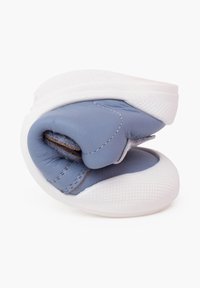 Blauer Lederschuh, zu einer kompakten Form gerollt. Verfügt über eine weiße Gummisohle mit strukturiertem Muster und kontrastierenden Nähten.