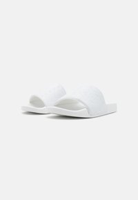 Hvite sandaler med glidesål og tekstureret overflade, der har prægede logoer. Åbent tå-design, flad sål og en glat finish.