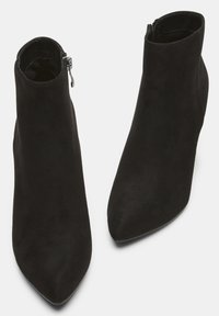 Stivaletti neri in suede con punta affusolata, chiusura con zip laterale e texture liscia. Design minimalista, versatile per vari outfit.