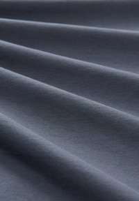 Ciemnoszara tkanina o gładkiej fakturze, z miękkimi, płynącymi fałdami i subtelnym połyskiem, idealna do odzieży lub tapicerki.