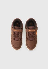 Sneakers sintetice maronii cu talpă albă, având un superior texturat, design cu șireturi, închidere cu curea și un accent de logo portocalie.
