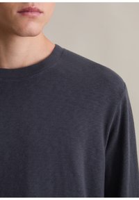 Dunkelgraues langärmeliges Shirt mit Rundhalsausschnitt. Weicher, leichter Stoff mit glatter Textur und minimalen Nähten.