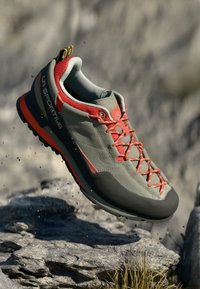 Leichte graue Wanderschuhe mit roten Akzenten und Schnürsenkeln, ausgestattet mit einer gepolsterten Sohle und einer verstärkten Zehenkappe, die für Outdoor-Aktivitäten konzipiert sind.