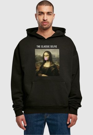 Fekete kapucnis pulóver, elülső grafikával a Mona Lisáról, aki rózsaszín rágógumit rág, felirattal: "A CLASSIC SELFIE." Pamut keverékből készült.