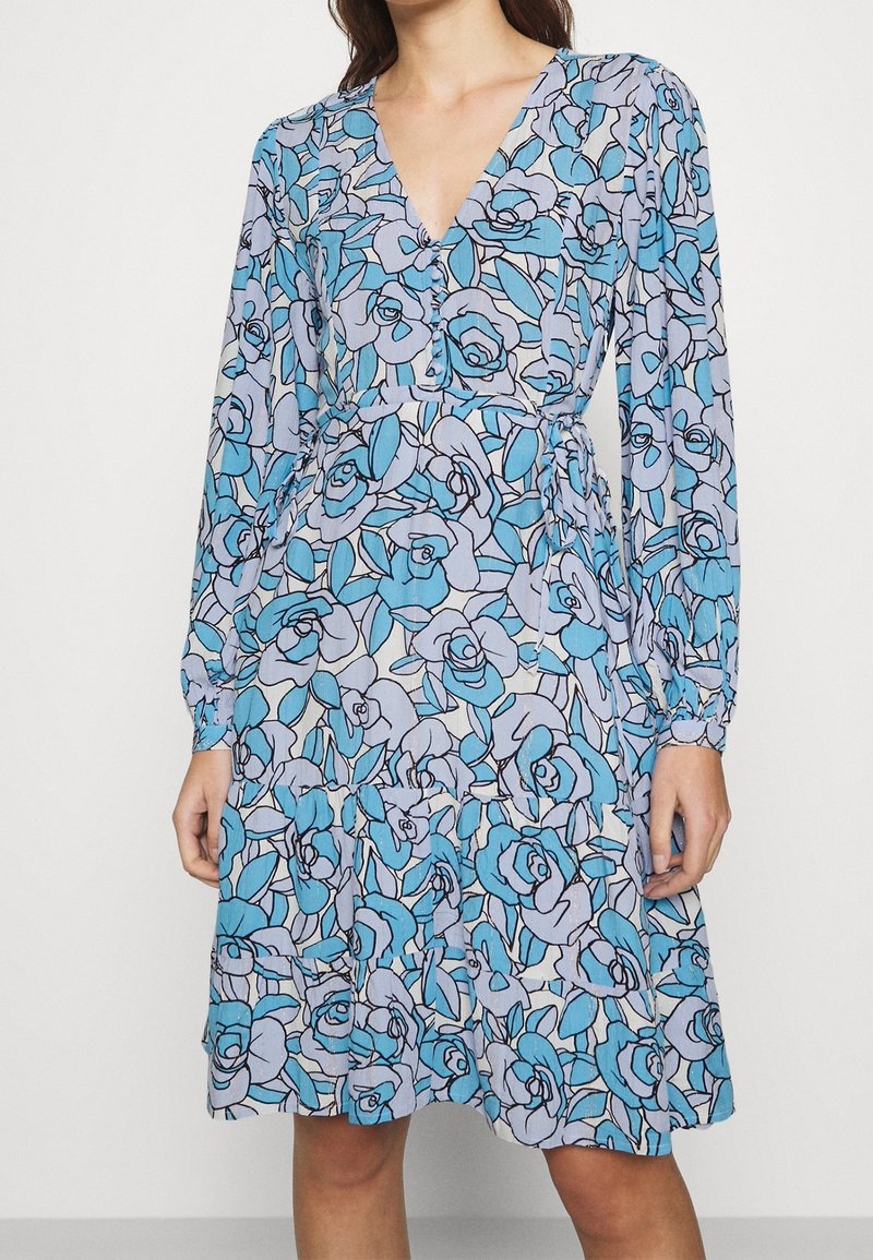 Blaues Blumenkleid mit V-Ausschnitt, langen Ärmeln und tailliertem Schnitt. Aus leichtem Stoff mit einem Muster aus Rosen und Blättern.