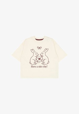 Flødefarvet T-shirt med to kaniner, der holder en kuvert med et hjerte og teksten "Hav en god dag!" nedenunder dem.