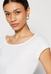 White cotton t-shirt with a wide, rounded neckline and short sleeves. Smooth texture and minimal design, featuring no patterns or accents.