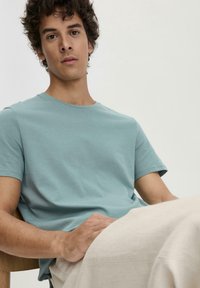 Lichtblauwe korte mouwen t-shirt van katoen, met een ronde halslijn en een relaxte pasvorm, gecombineerd met beige broeken. Minimalistisch ontwerp.