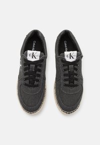 Sneakers in tela nera con lacci neri, punta rotonda, suola cucita in contrasto e logo sulla linguetta. Tessuto testurizzato e design casual.