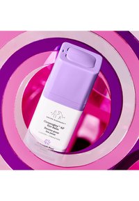 Ceramighty AF eye balm, cylindrical white container with a purple cap, displayed against vibrant pink and purple concentric circles.