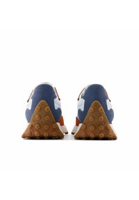 Zapatos deportivos con un upper de ante azul, acentos blancos, detalles naranjas y una suela de goma marrón texturizada con forma triangular y puntos.