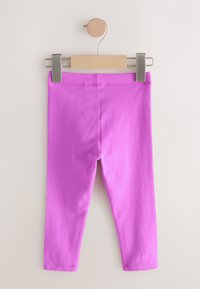 Roosad puuvillased retuusid, mis ripuvad puidust nagil. Omavad elastset vööd ja keha järgivat lõiget, sileda tekstuuriga ning ilma mustriteta.