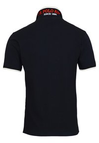 Polo negro con un logo blanco y rojo en el cuello, mangas cortas con acentos blancos y una textura sólida.