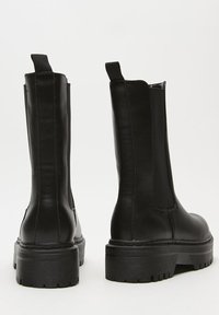 Black leather ankle boots with a chunky rubber sole, side stretch panels, and pull tabs for easy wear. Smooth texture with a sleek design.