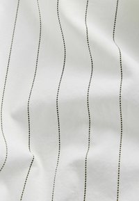 Țesătură albă cu dungi verticale negre, având o textură netedă și linii punctate uniform distribuite, creând un model pe toată suprafața.