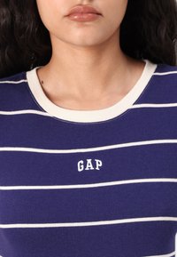 Marine stribet kortærmet skjorte med ribbet tekstur og hvide detaljer. Har en rund halsudskæring og "GAP" logo i hvid på forsiden.
