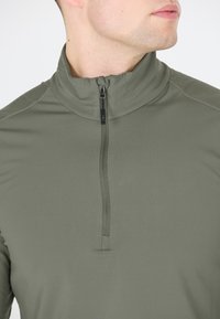 Quarter-zip, langærmet top i olivengrøn, lavet af glat, strækbart stof med subtile sømdetaljer og en høj krave.